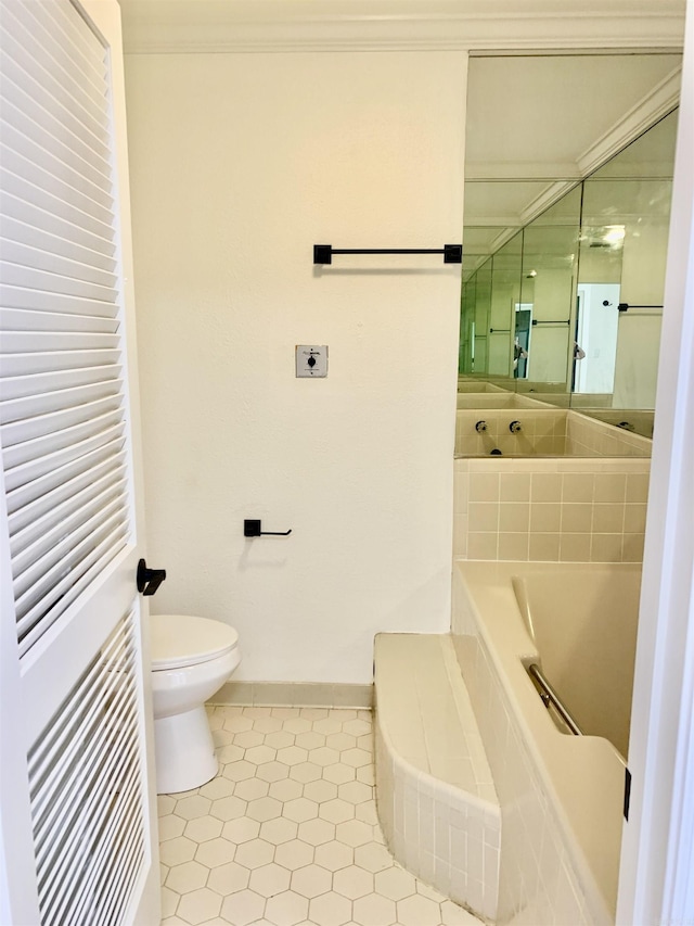 bathroom with tile patterned floors, toilet, ornamental molding, baseboards, and a garden tub