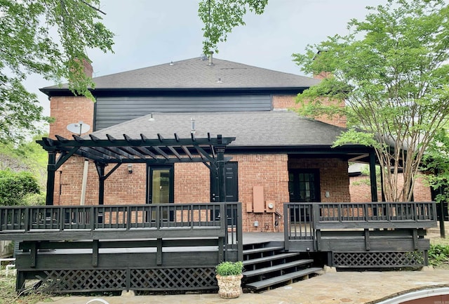 rear view of house featuring roof with shingles, a pergola, a chimney, brick siding, and a wooden deck