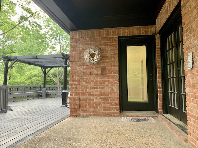 doorway to property featuring brick siding and a wooden deck