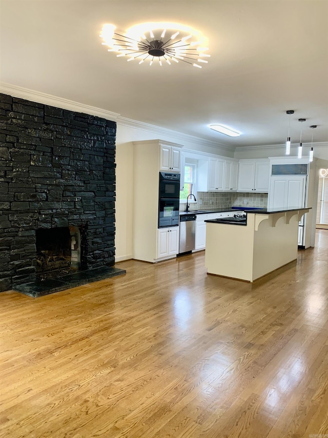kitchen with white cabinets, stainless steel dishwasher, ornamental molding, and a sink