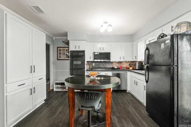 kitchen with decorative backsplash, black appliances, visible vents, dark countertops, and dark wood finished floors