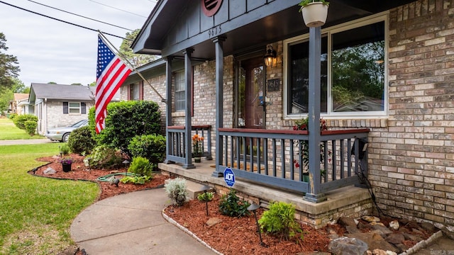 view of exterior entry with a porch and a lawn