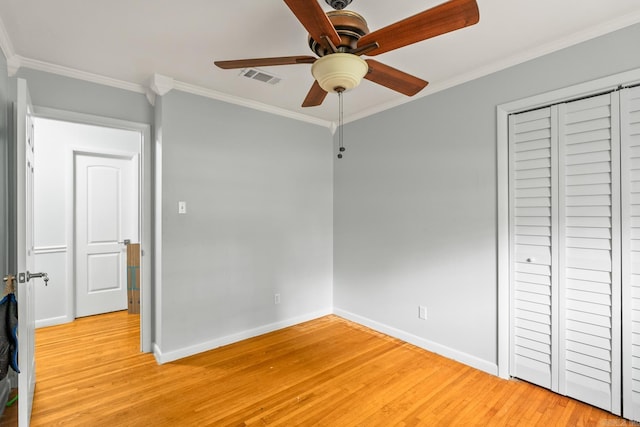 unfurnished bedroom featuring visible vents, a closet, baseboards, light wood-type flooring, and ornamental molding
