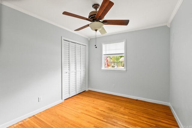 unfurnished bedroom with crown molding, light wood-style flooring, a closet, baseboards, and a ceiling fan