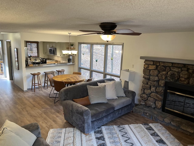 living room featuring wood finished floors, a textured ceiling, and ceiling fan