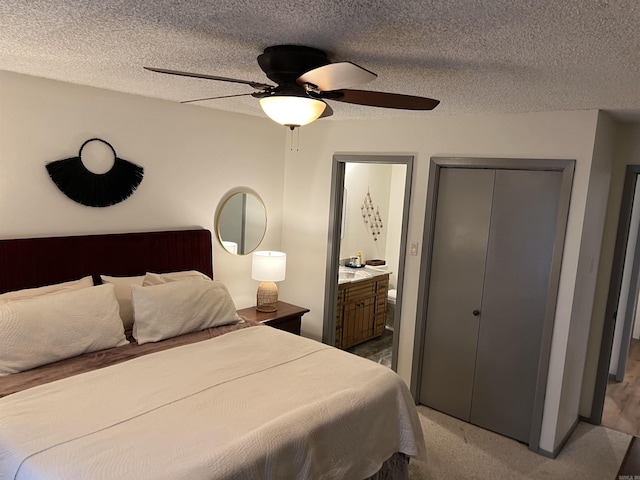 carpeted bedroom with ensuite bathroom, a textured ceiling, a closet, and ceiling fan