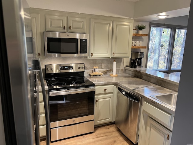 kitchen with white cabinets, stainless steel appliances, light countertops, open shelves, and tasteful backsplash