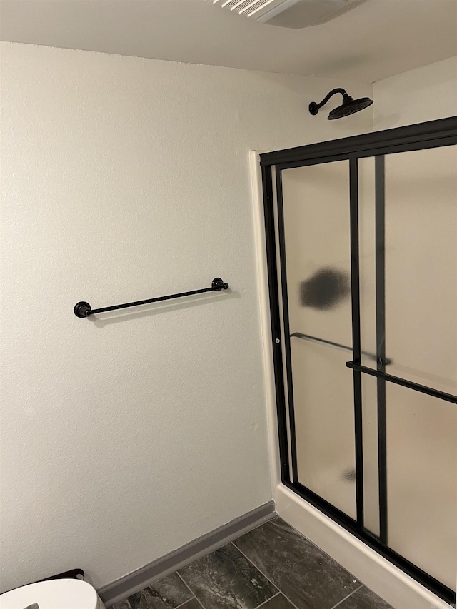 bathroom featuring an enclosed shower, toilet, and baseboards