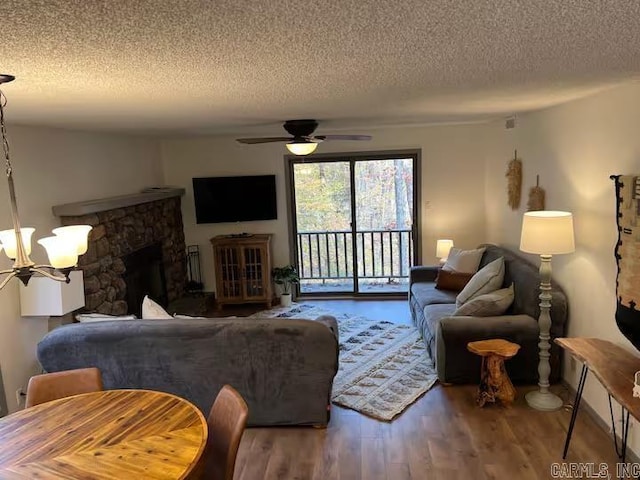 living room featuring wood finished floors, a textured ceiling, and ceiling fan with notable chandelier