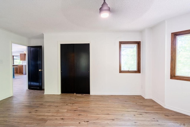 unfurnished bedroom with wood finished floors, a textured ceiling, and a closet