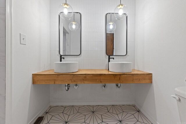 bathroom with double vanity, tile patterned flooring, baseboards, and a sink