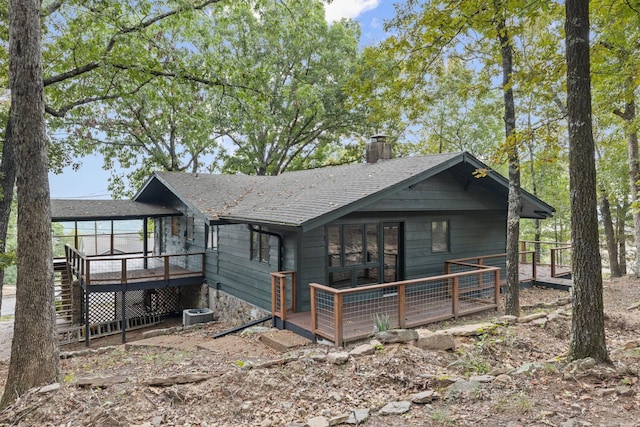 back of house with a wooden deck, a shingled roof, a chimney, and central AC unit