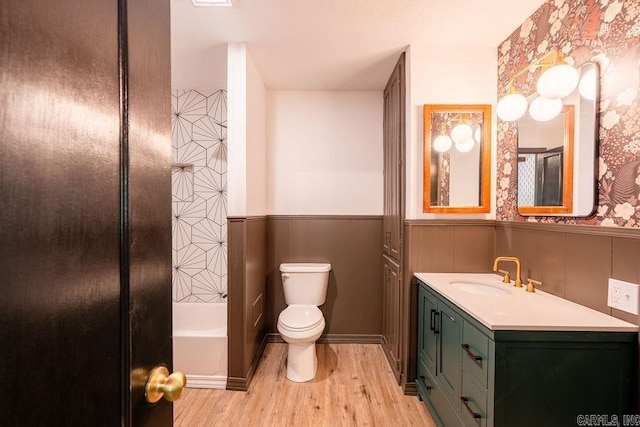 bathroom featuring wood finished floors, a wainscoted wall, vanity, and toilet