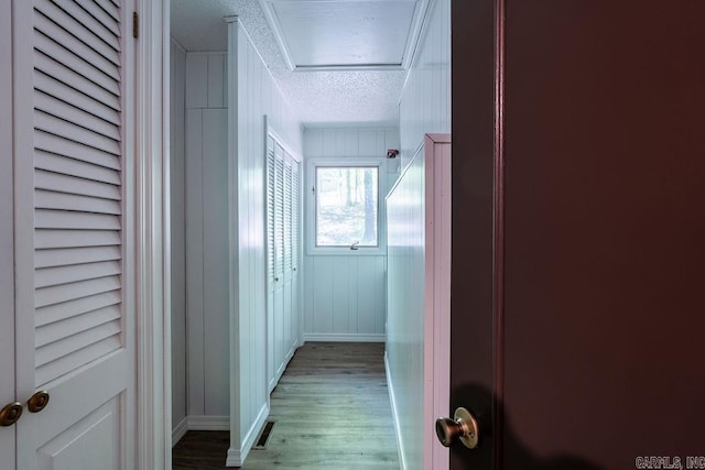 hall featuring baseboards, a textured ceiling, and light wood-style floors