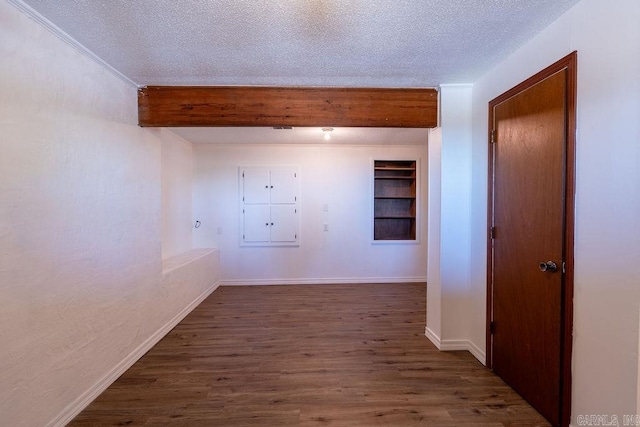 hall featuring dark wood-type flooring, beamed ceiling, baseboards, a textured ceiling, and built in shelves