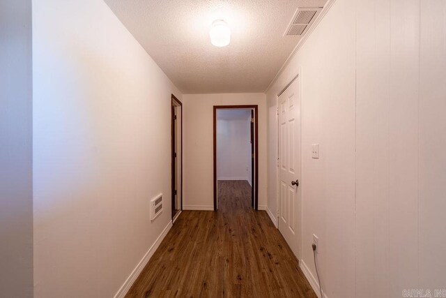 corridor featuring baseboards, visible vents, a textured ceiling, and dark wood-type flooring