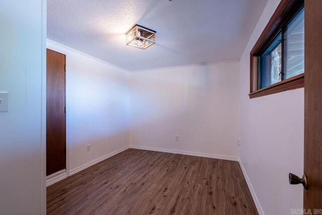 empty room with wood finished floors, a textured ceiling, and baseboards