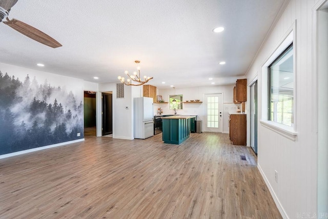 kitchen featuring light wood finished floors, open floor plan, baseboards, freestanding refrigerator, and recessed lighting