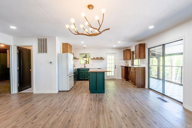 kitchen with a notable chandelier, a sink, visible vents, and freestanding refrigerator
