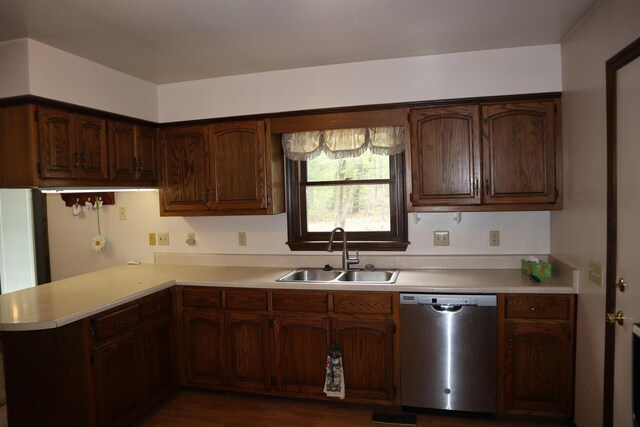 kitchen featuring a peninsula, light countertops, a sink, dishwasher, and dark wood-type flooring