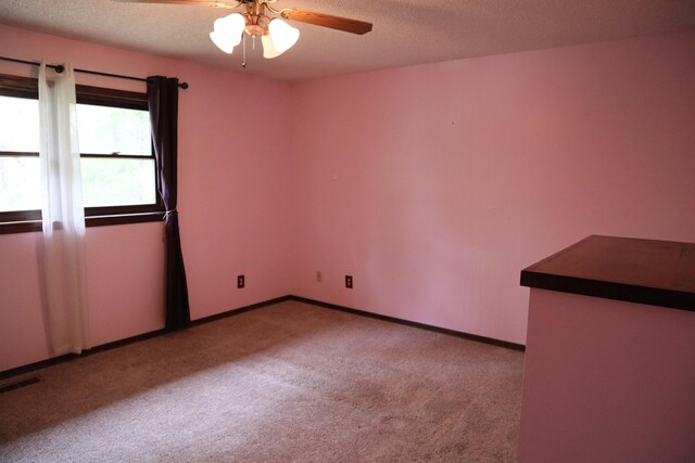 spare room featuring ceiling fan, carpet flooring, a textured ceiling, and visible vents