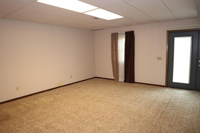empty room with a paneled ceiling, baseboards, and light carpet