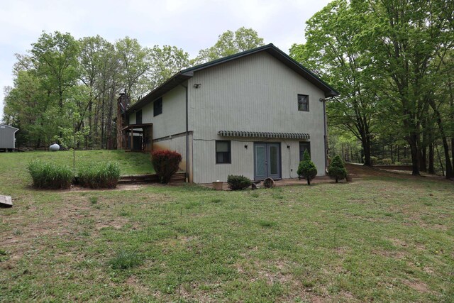 rear view of property with a chimney, a yard, and french doors