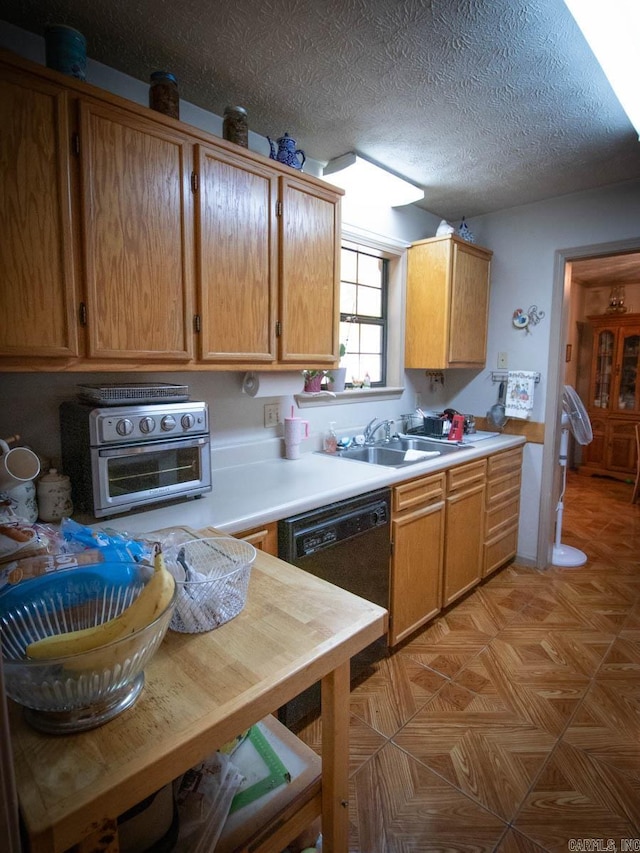 kitchen featuring brown cabinets, a toaster, light countertops, a sink, and a textured ceiling