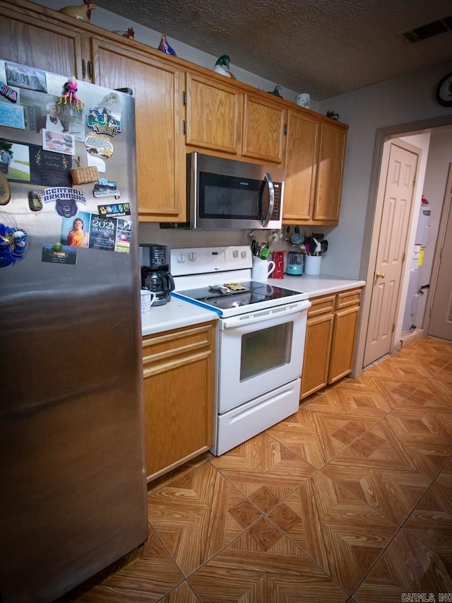 kitchen with stainless steel appliances, light countertops, visible vents, and brown cabinetry