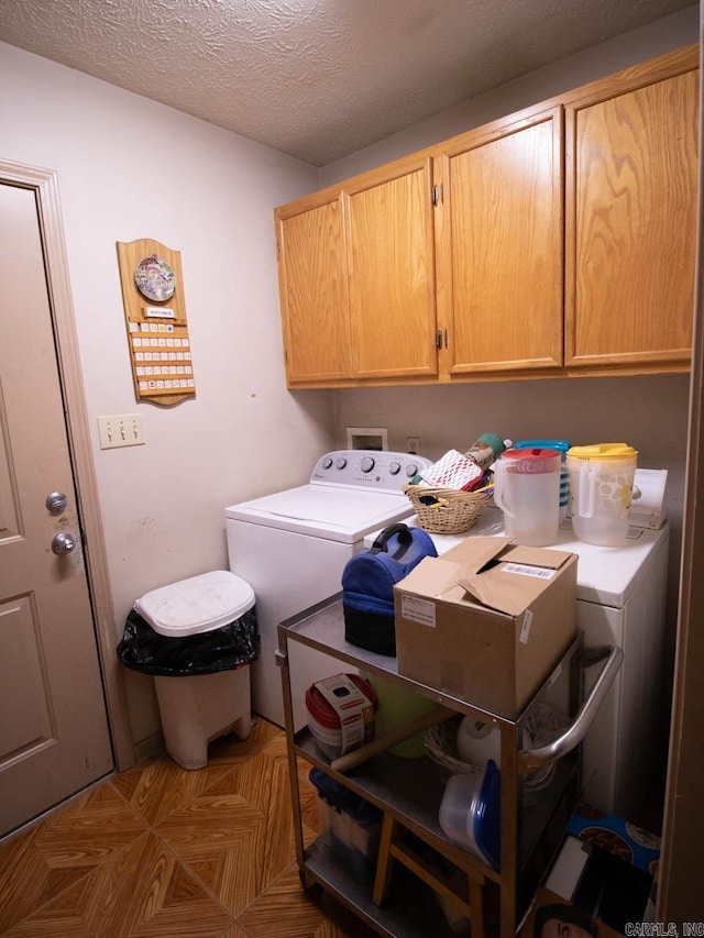 laundry area with washing machine and dryer, a textured ceiling, and cabinet space