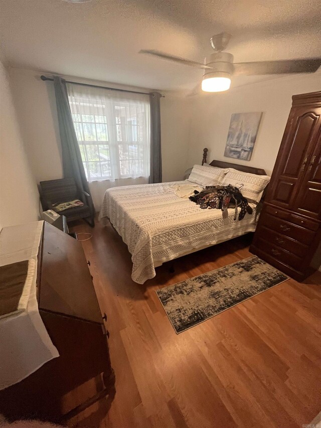 bedroom featuring wood finished floors, a textured ceiling, and a ceiling fan