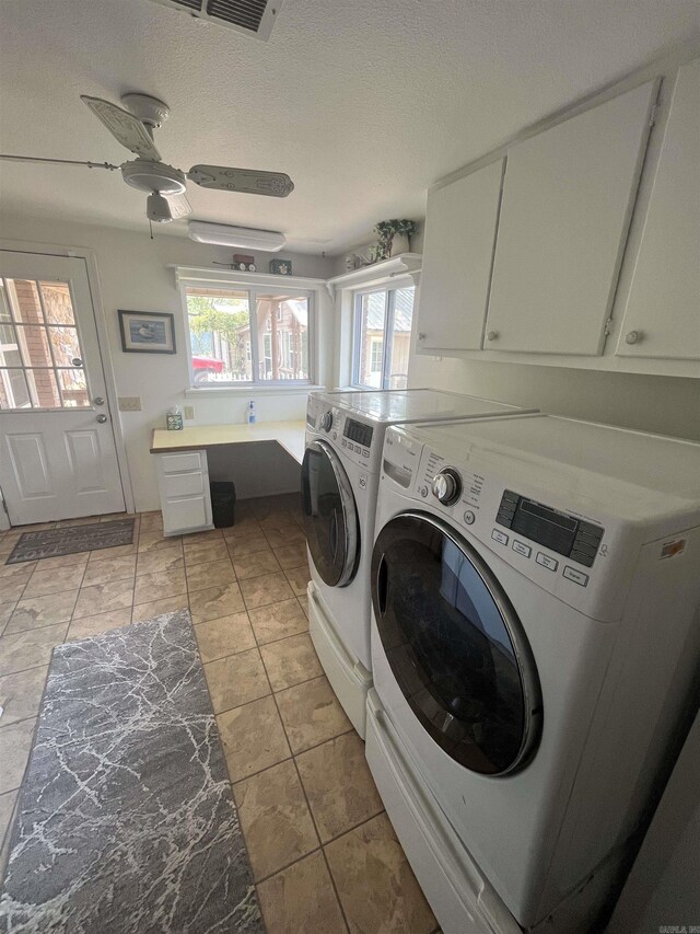 laundry room featuring washing machine and clothes dryer, a textured ceiling, ceiling fan, cabinet space, and visible vents