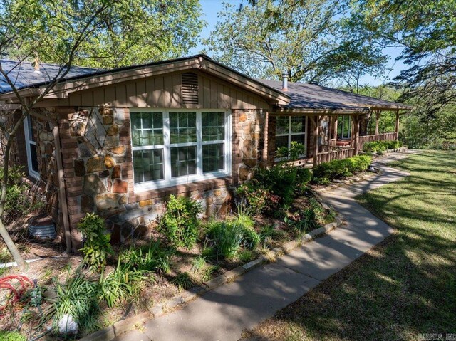 view of home's exterior with stone siding, a lawn, and roof with shingles