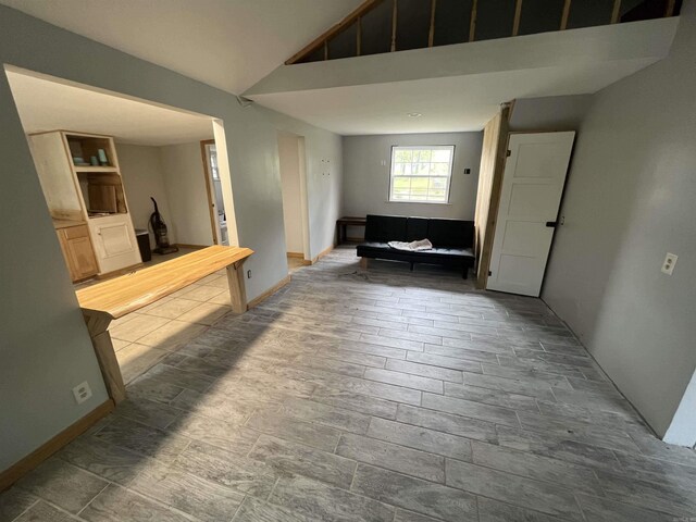 unfurnished living room with baseboards and high vaulted ceiling