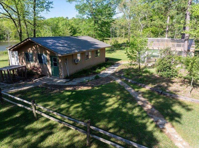 view of front facade with a wooded view, cooling unit, a front lawn, and metal roof