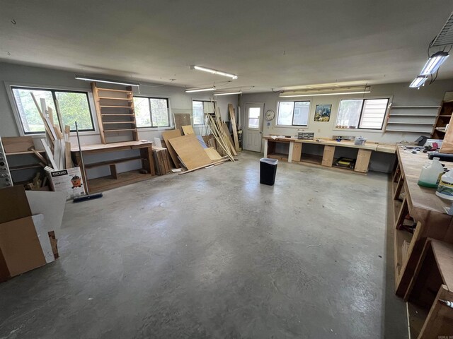 interior space featuring concrete flooring, a workshop area, and a healthy amount of sunlight