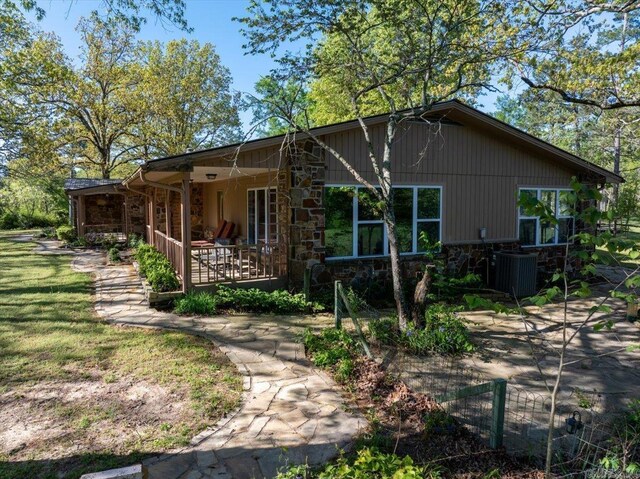 exterior space featuring stone siding, covered porch, and central air condition unit