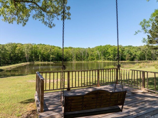 deck with a yard, a view of trees, and a water view