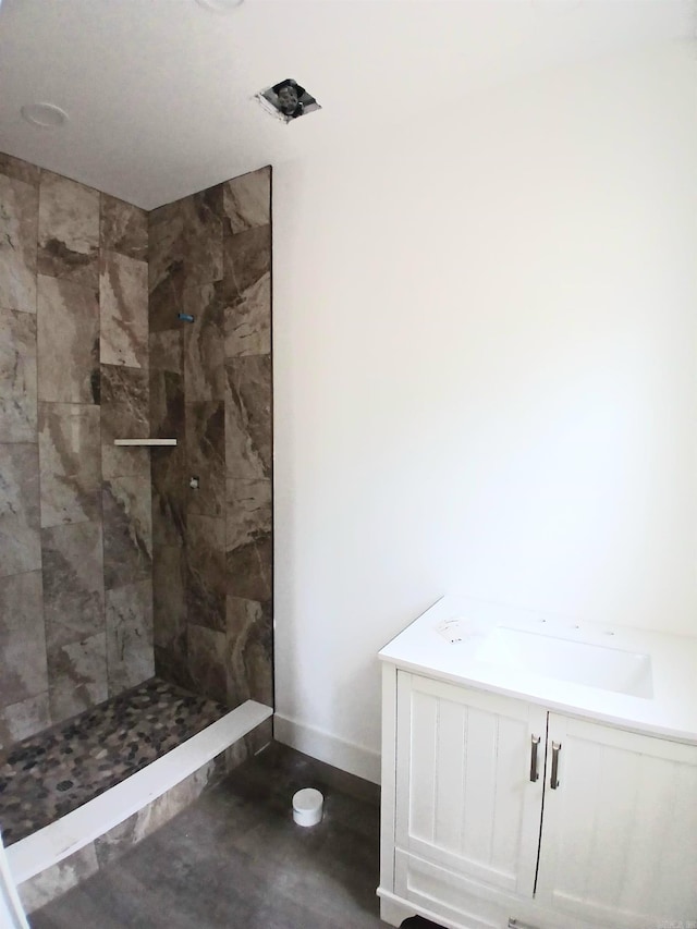bathroom with tiled shower and baseboards