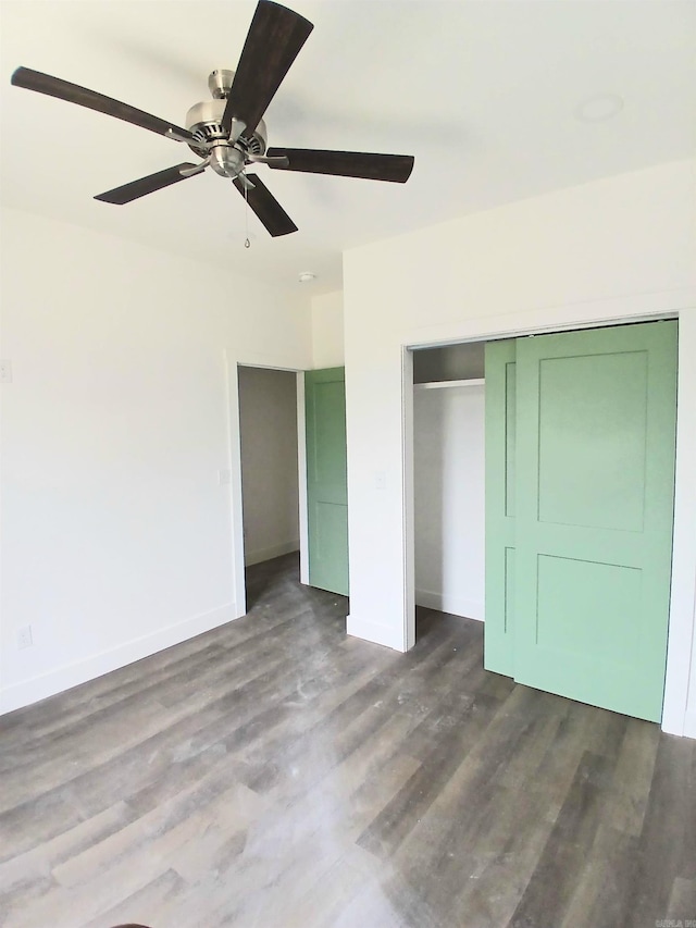 unfurnished bedroom with baseboards, dark wood finished floors, a closet, and a ceiling fan