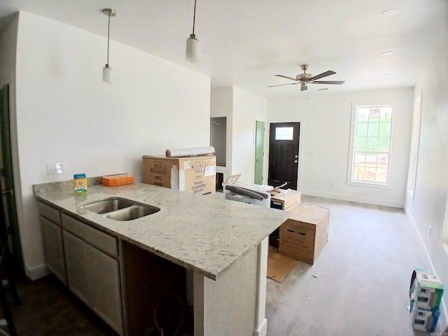 kitchen featuring a peninsula, pendant lighting, light stone countertops, and a ceiling fan