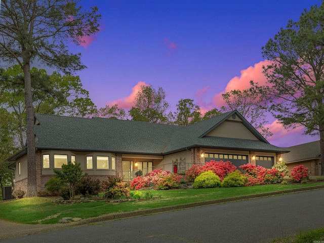 single story home with brick siding, a yard, a shingled roof, and a garage