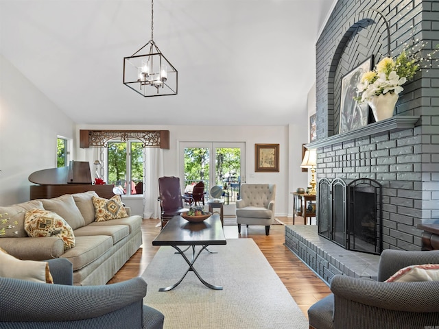 living area with a chandelier, light wood-type flooring, a brick fireplace, and high vaulted ceiling