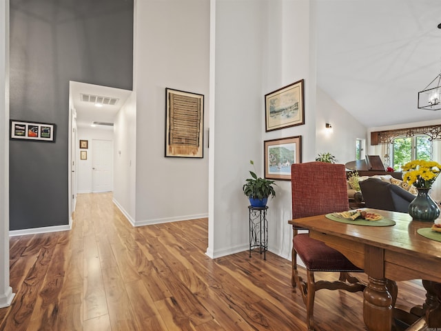 dining space featuring wood finished floors, visible vents, and high vaulted ceiling