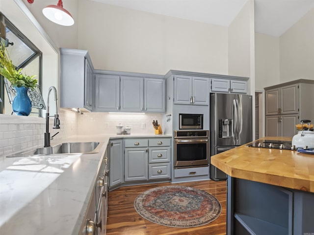 kitchen featuring gray cabinets, stainless steel appliances, dark wood-style floors, and a sink