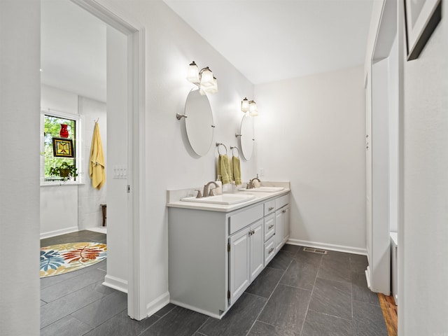 bathroom featuring double vanity, visible vents, baseboards, and a sink