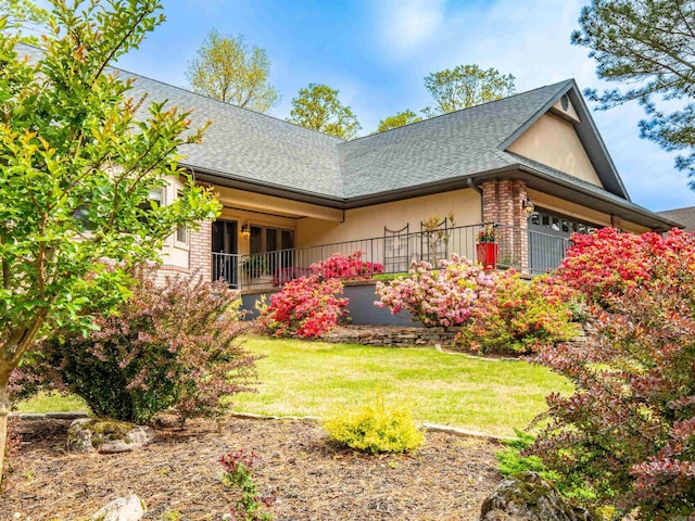 view of side of home with a yard, a shingled roof, and stucco siding