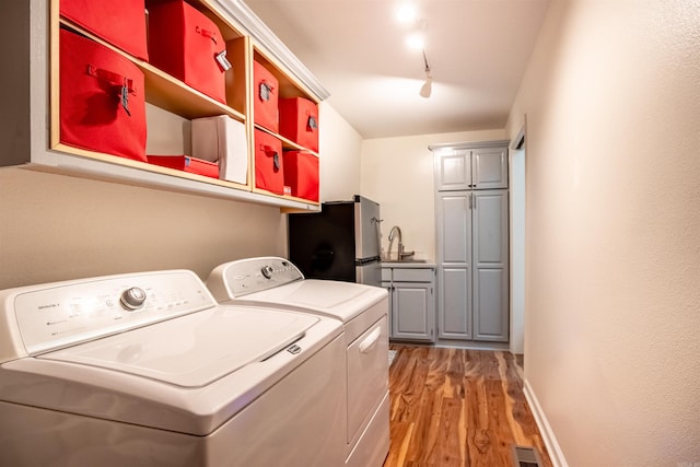 laundry area with separate washer and dryer, laundry area, light wood finished floors, rail lighting, and visible vents