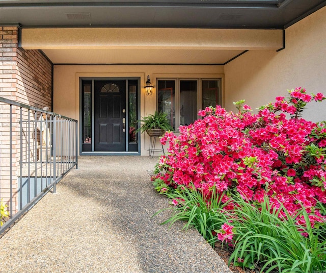 property entrance featuring a porch, brick siding, and stucco siding