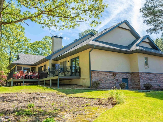 view of side of property featuring brick siding, a lawn, stucco siding, and a deck